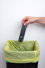Person throwing used and broken TV remote in the trash.