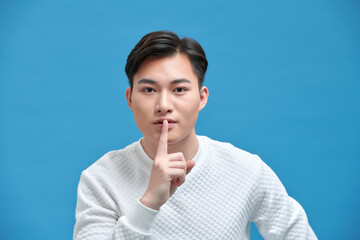 Young handsome man showing a sign of silence gesture putting finger in mouth