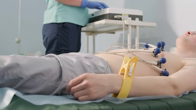 Cardiac examination in a hospital with a professional cardiograph. The patient lies on a bed with connected sensors.