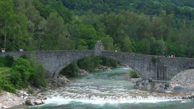 Gobbo bridge over Trebbia river, Bobbio in Italy. Aerial backward ascending