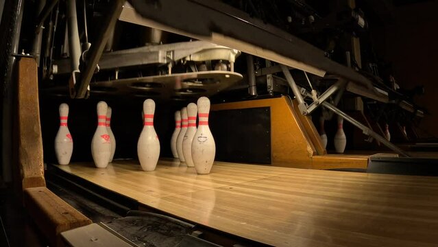 Pinsetter placing bowling pins in place then a ball knocks down mine - isolated close up