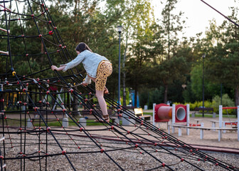 A happy girl at a playground. The girl is playing on net ropes.
