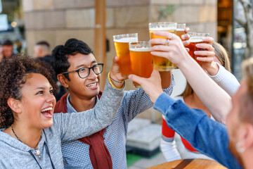 Cheerful diverse friends clinking glasses of beer
