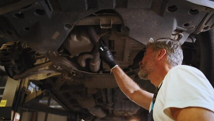 Car diagnostics. Auto service. Skillful professional middle age master performs maintenance, oil change, computer diagnostics, replacement of auto parts, repair of brake system. Auto mechanic.