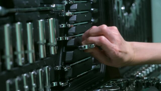 Women's hands take out a wrench from a set of car tools. Female mechanic taking tool from toolbox in auto shop. High quality 4k footage. Sockets and Wrenches in Workshop Drawer. 