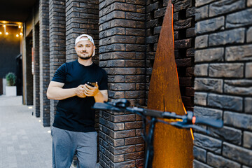 Handsome man using smartphone app. Guy approaches an electric scooter and using mobile phone app NFC contactless locker on bike bicycle in sharing parking lot. Ecological transportation