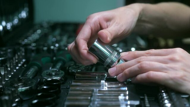 Women's hands take out a socket from a set of car tools. Female mechanic taking tool from toolbox in auto shop. High quality 4k footage. The buyer checks the set of tools for the purchase. Close-up