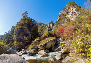 Mountains Japan. City Kofu. Landscape of national park. River in mountains. Kofu park in sunny weather. Tour to Japan. Multi-colored trees on rocks. Kofu region in province of Japan. Autumn landscape