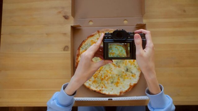 Four Cheese Delicacy. Top view - Female hands use digital camera photographing appetizing fresh cooked italian Quattro Formaggi Pizza on wooden background. Food blog of blogging. Technology, food porn