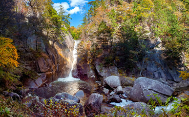 Obraz premium Regions of Japan. Kofu park. Waterfall in rocky area. Autumn landscape. Kofu national park. Nature of Japan in sunny weather. Japanese rocks are covered with trees. Maizuru castle park. Tour in Japan