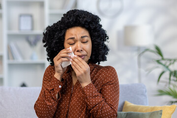 Fototapeta na wymiar Portrait of a young African American woman at home crying, wiping tears with a napkin, suffering from depression, received bad news about death. He has health problems and financial problems