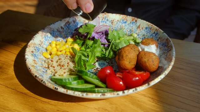 Chickpea falafel salad with vegetables, quinoa and Edamame beans with Zaziki sauce on a wooden table. Healthy vegetarian food. Bright, juicy fresh rations. High quality 4k footage. Healthy lifestyle