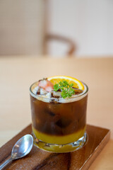 A glass of iced americano black coffee and layer of orange with sliced orange fruit