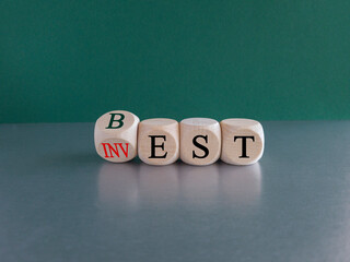 Best invest symbol. Turned a wooden cube and changes red word Invest to Best. Beautiful grey table, green background. Business and best invest concept. Copy space