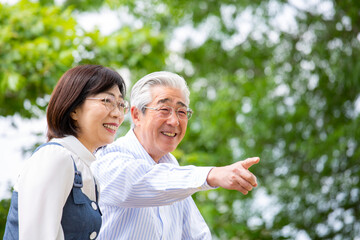 公園のベンチ、笑顔で会話する日本人のミドル夫婦