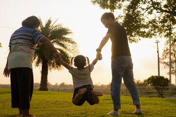 Silhouette, diversity of young women and girls walking in the park with LGBTQ family. Family enjoying outdoor activities behind the garden in the evening.