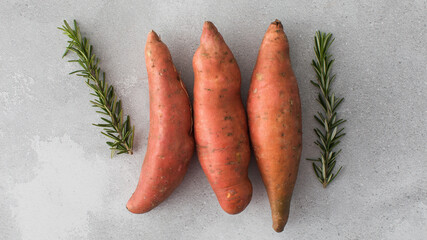Fototapeta Raw sweet potatoes on a grey background. Orange kumara, yam. Healthy eating. obraz