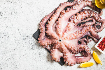 raw fresh octopus on gray stone with lemon and pink pepper