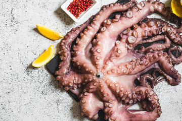 raw fresh octopus on gray stone with lemon and pink pepper