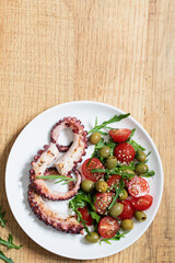 salad with octopus, tomatoes, olives and arugula. fresh healthy salad