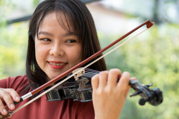 An attractive woman learning musician plays the violin at home.  Composer creating songs with...