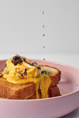 Classic Croque Madame with poached egg and ham in a bowl on a gray background