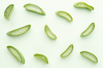 Top view of fresh aloe vera leaf slice with water drops over green background. Gel from the leaves of aloe plants used for medicine and skin care.