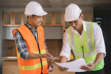 Architecture and teamwork concept. Male engineers or business partners on a construction site, discussing project details.