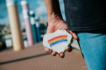 man has a rock with a rainbow flag in his hand