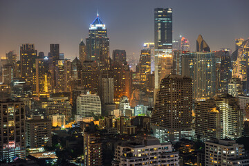 Night urban cityscape skyline of modern illuminated Bangkok city with glowing skyscrapers and buildings in dusk. High-angle view on colorful Metropolis lights in twilight