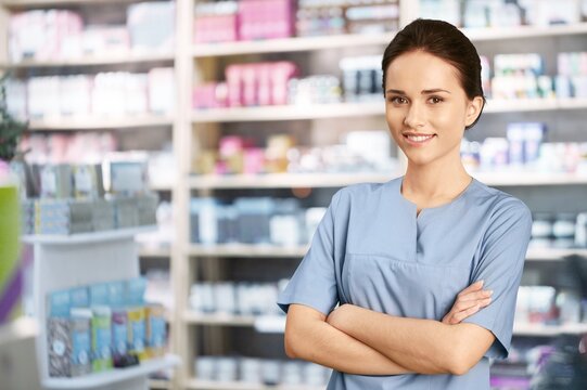 Young happy woman pharmacist standing at pharmacy