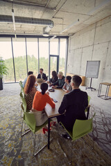 A diverse group of business professionals gathered at a modern office for a productive and...