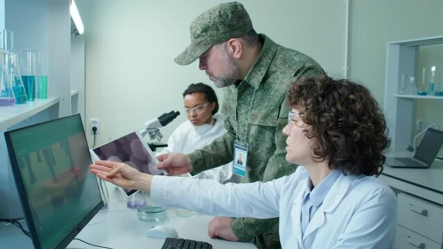High angle of female scientist showing military man with photo of cells in hand results of top secret research in laboratory at daytime