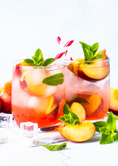 Peach cocktail, iced peach tea, fruit drink, summer beverage with fresh fruits and mint.