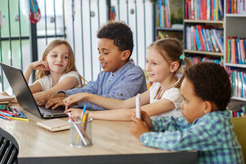 Obraz premium Multiracial group of children sitting in row at school classroom and using laptops. Back to school.