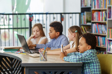 Multiracial group of children sitting in row at school classroom and using laptops. Back to school.