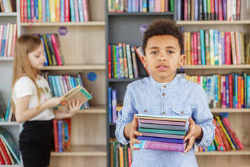 Afro american child boy choosing books in school library. Benefits of everyday reading.