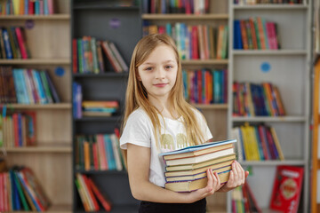 Child buys books in bookstore for learning or reading. Girl choosing book in school library.