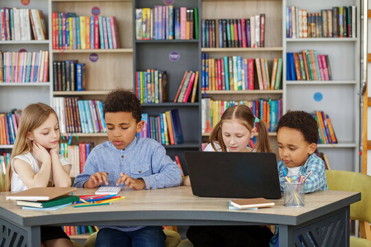 Multiracial group of children sitting in row at school classroom and using laptops. Back to school. - Powered by Adobe