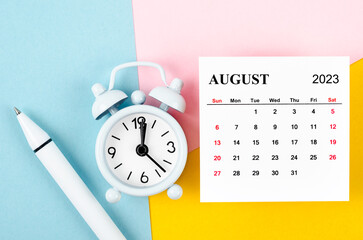 The August 2023 Monthly calendar with alarm clock and pen on beautiful background.