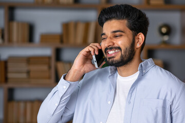 Happy smiling indian professional business man talking on cell phone, eastern businessman making mobile phone call by cellphone in office.