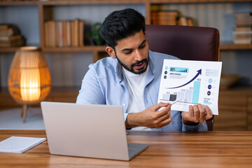 Online meeting concept. Young arab man having video call on laptop computer, showing statistics and market reports to webcam.