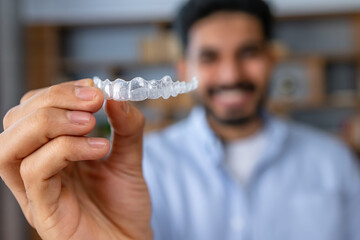 Man showing an invisible silicone aligner for dental correction. Male hand holding the plastic braces dentistry retainers to straighten teeth - 610646852