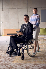 A businessman in a wheelchair and his female colleague together in a modern office, representing the power of teamwork, inclusion and support, fostering a dynamic and inclusive work environment.