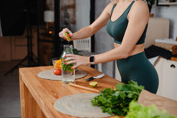 Close up view of attractive sporty woman body in green activewear cooking salad