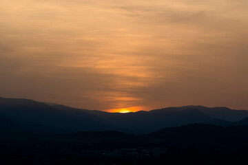 Fototapeta na wymiar Atardecer con el sol escondiéndose entre las montañas