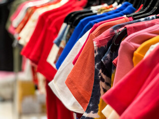 Closeup group of colorful t-shirts hanging on the rack for sale in the shop