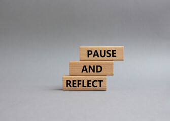 Pause and Reflect symbol. Concept words Pause and Reflect on wooden blocks. Beautiful grey background. Business and Pause and Reflect concept. Copy space.