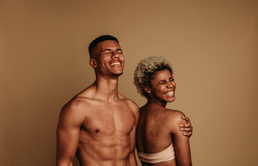 Happy, fit couple stands together in a studio