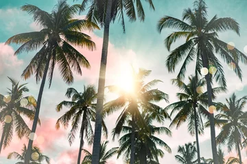 Fotobehang Strand zonsondergang Tropical palm coconut trees on sunset sky flare and bokeh nature background.